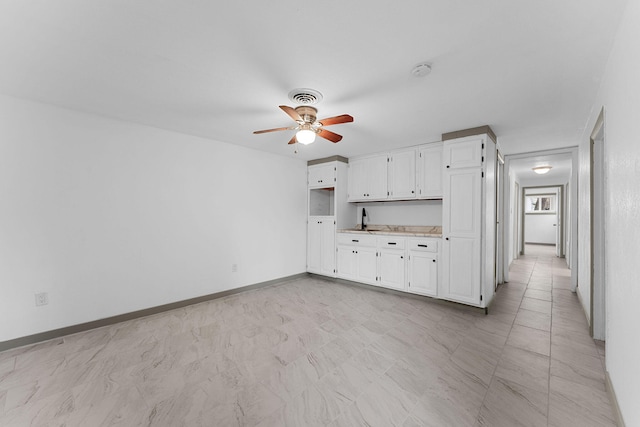 kitchen with white cabinetry, sink, and ceiling fan