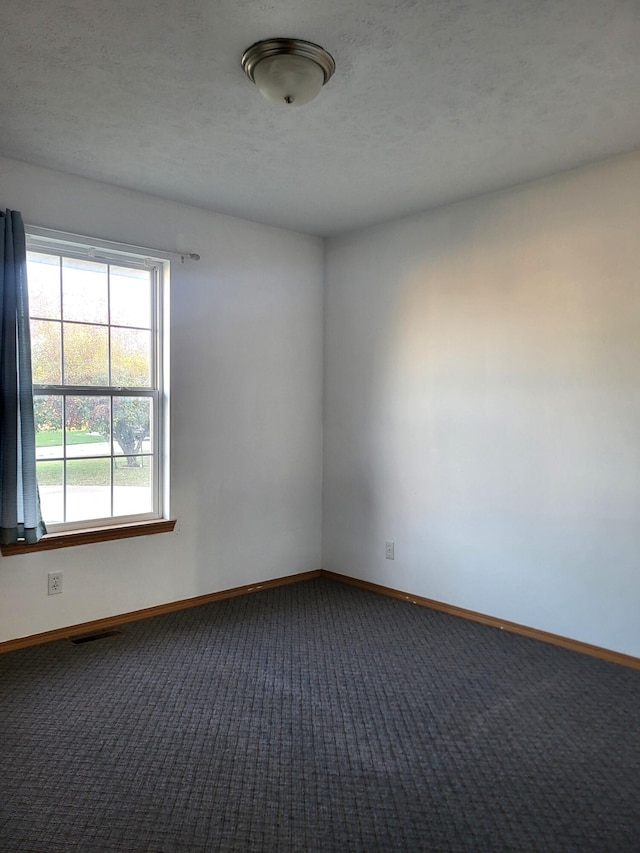 carpeted spare room with a textured ceiling