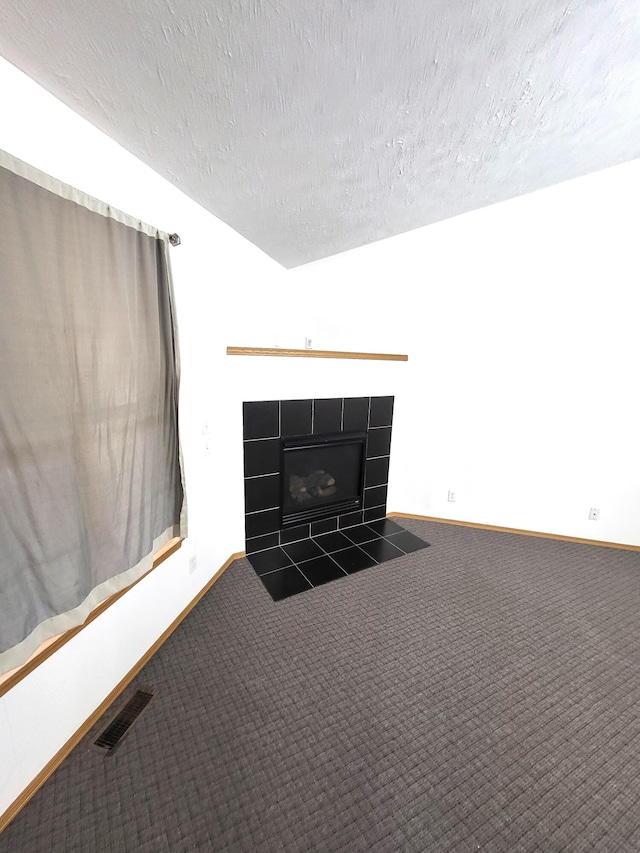 details featuring a tiled fireplace, a textured ceiling, and carpet