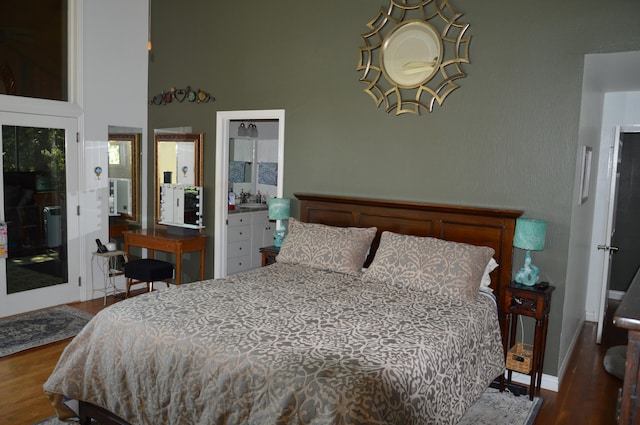 bedroom featuring dark wood-type flooring, a high ceiling, and connected bathroom