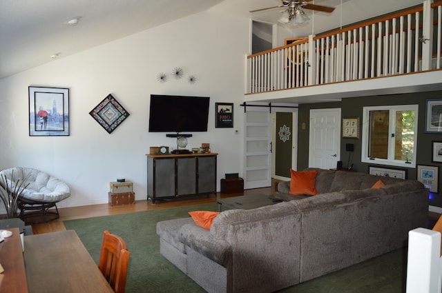 living room with high vaulted ceiling, wood-type flooring, a barn door, and ceiling fan