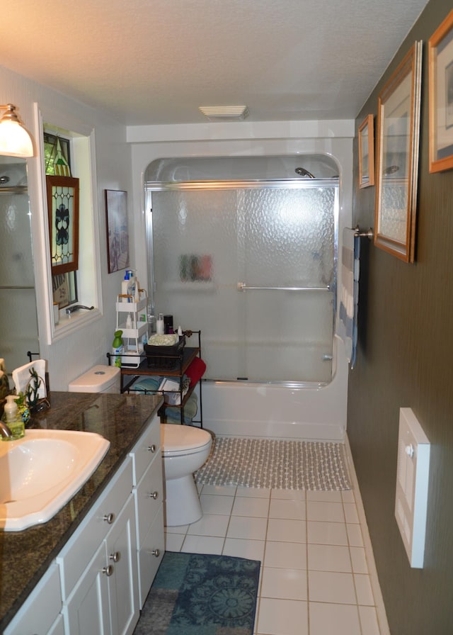 full bathroom with tile patterned flooring, vanity, combined bath / shower with glass door, and toilet