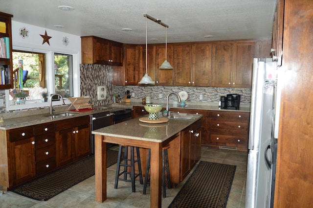 kitchen with an island with sink, light stone countertops, sink, and white fridge