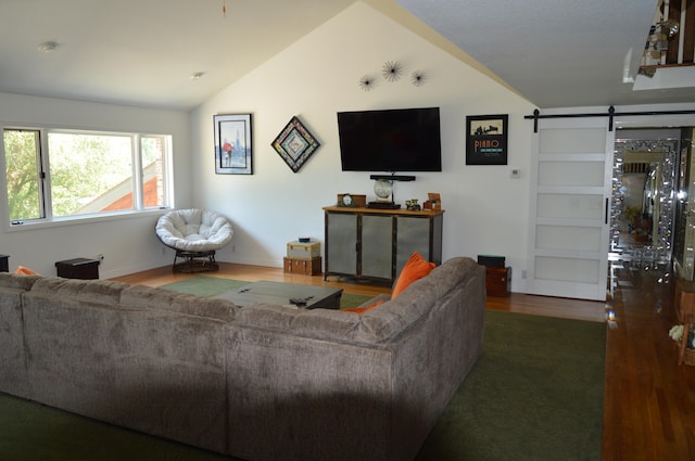 living room featuring dark hardwood / wood-style flooring, lofted ceiling, and a barn door