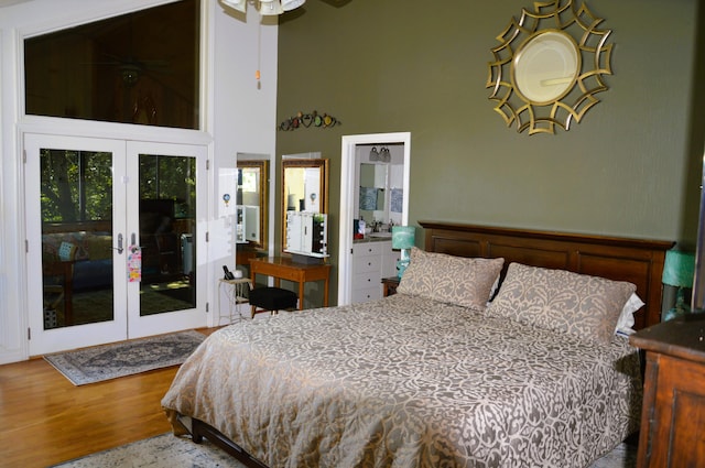 bedroom with a towering ceiling, wood-type flooring, french doors, and access to outside