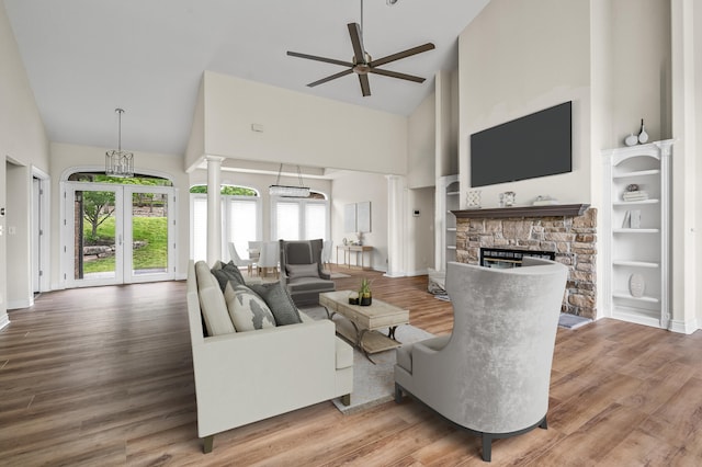 living room with high vaulted ceiling, a stone fireplace, and wood-type flooring