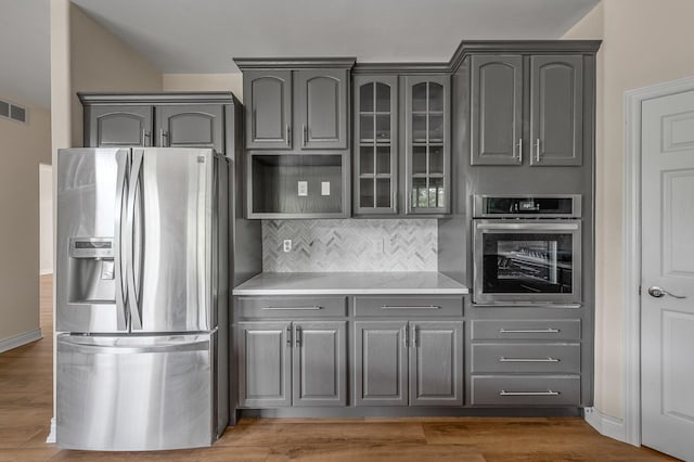 kitchen with gray cabinets, appliances with stainless steel finishes, backsplash, and dark hardwood / wood-style flooring