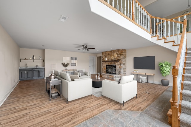 living room with hardwood / wood-style flooring, ceiling fan, a stone fireplace, and sink