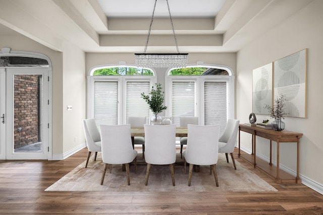 dining space featuring dark hardwood / wood-style floors, a notable chandelier, and a tray ceiling