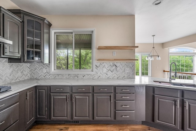 kitchen with dark wood-type flooring, sink, backsplash, and light stone countertops