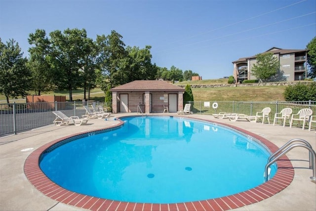 view of swimming pool featuring an outbuilding and a patio