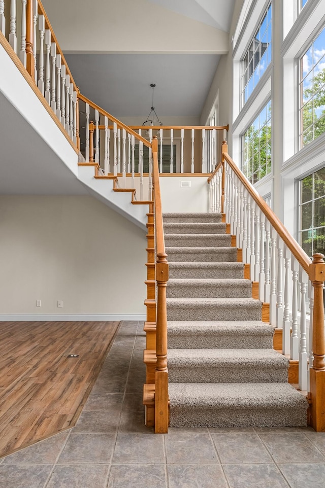 stairway with hardwood / wood-style floors and high vaulted ceiling