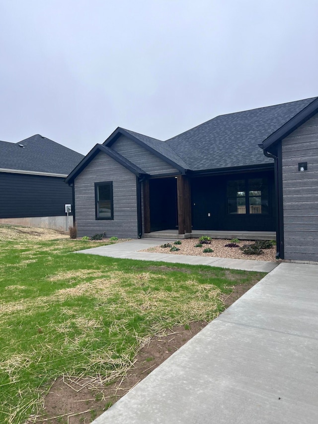 view of front of house featuring a shingled roof and a front lawn