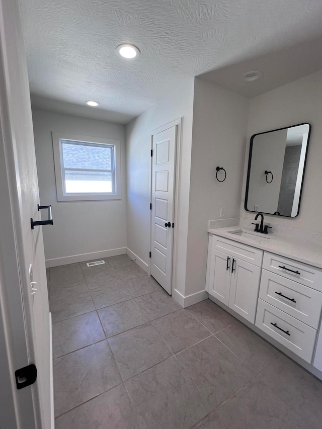 bathroom featuring a textured ceiling, tile patterned flooring, visible vents, vanity, and baseboards