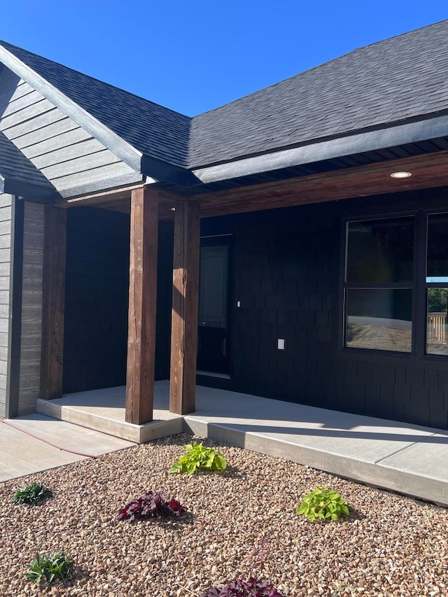 view of exterior entry with a shingled roof