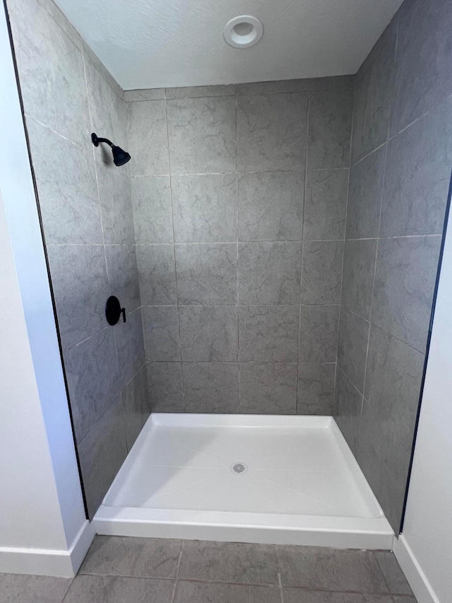 bathroom featuring baseboards and tiled shower