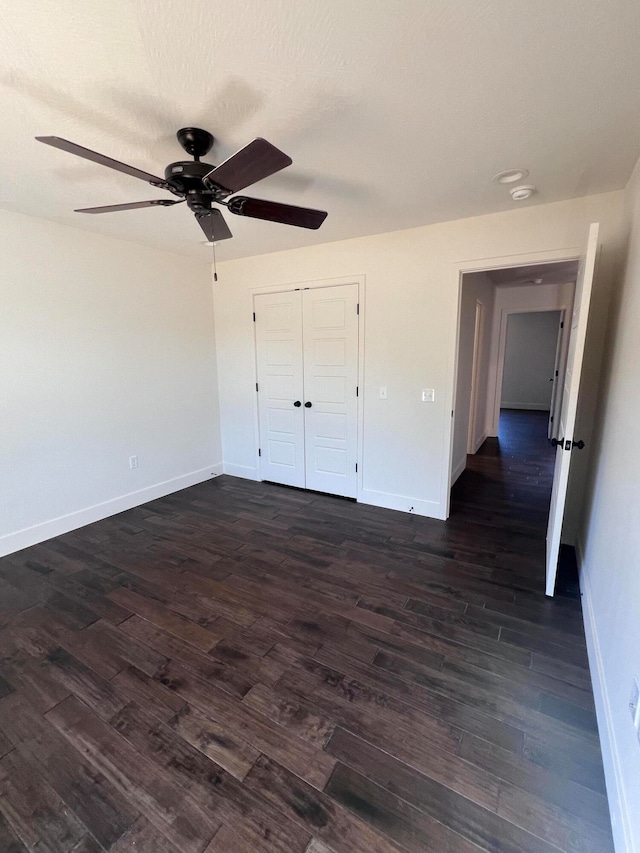 unfurnished bedroom with a closet, dark wood finished floors, baseboards, and ceiling fan