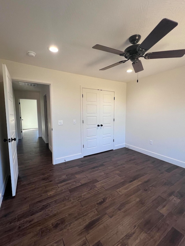 unfurnished bedroom with baseboards, dark wood finished floors, a closet, and recessed lighting