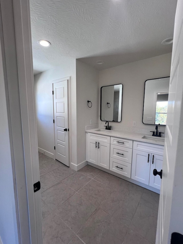 full bathroom featuring a sink, baseboards, and double vanity