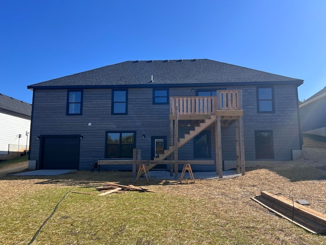 back of house featuring stairs, a yard, roof with shingles, and an attached garage