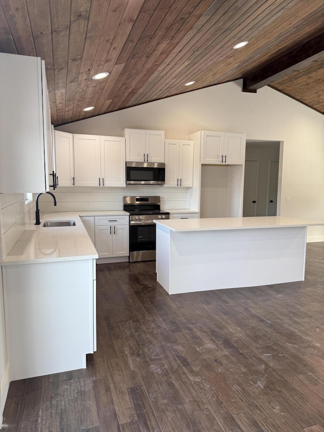 kitchen with stainless steel appliances, white cabinetry, a sink, and lofted ceiling with beams