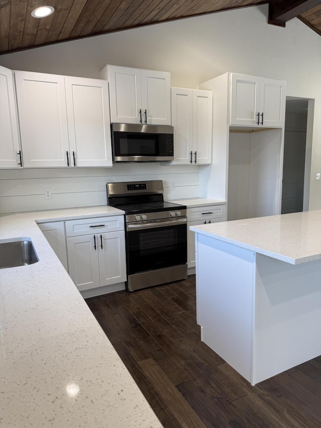 kitchen featuring lofted ceiling with beams, appliances with stainless steel finishes, dark wood-type flooring, and white cabinetry