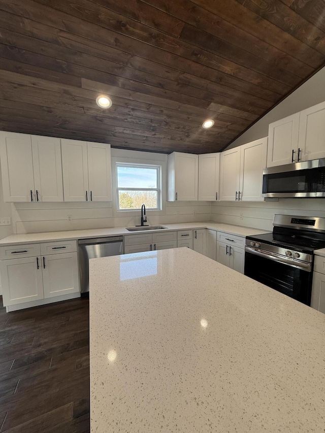 kitchen with white cabinets, lofted ceiling, wood ceiling, appliances with stainless steel finishes, and a sink