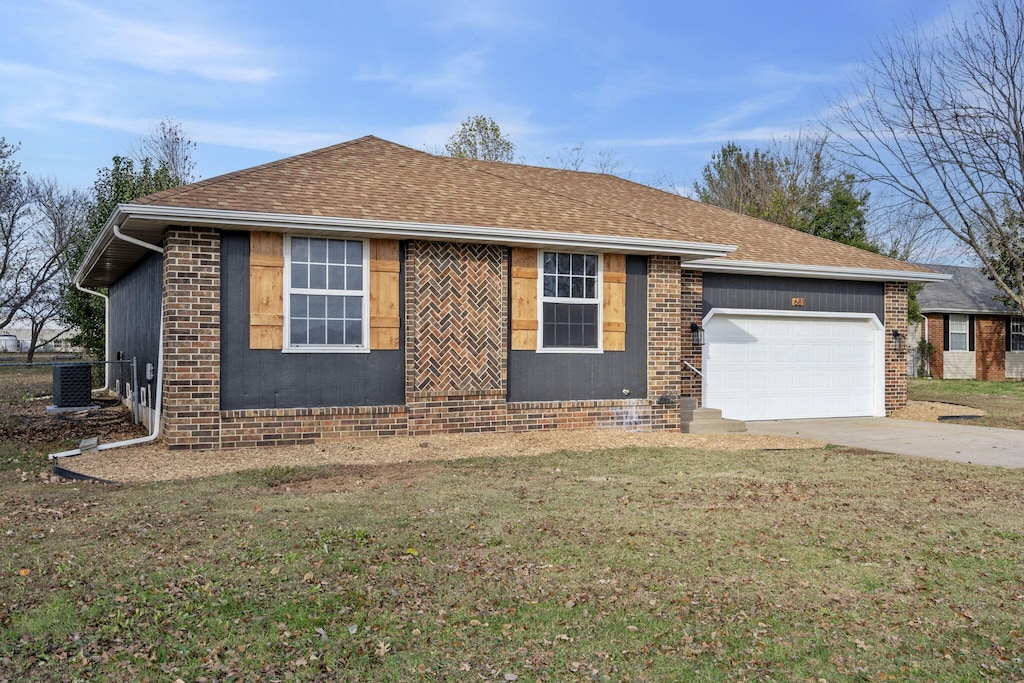 single story home with central air condition unit, a garage, and a front lawn