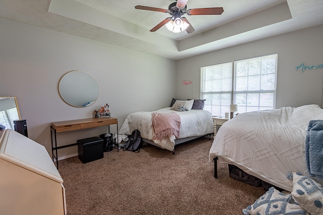 carpeted bedroom with ceiling fan and a raised ceiling