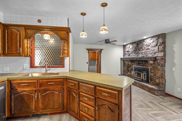 kitchen featuring decorative light fixtures, kitchen peninsula, sink, and a wood stove