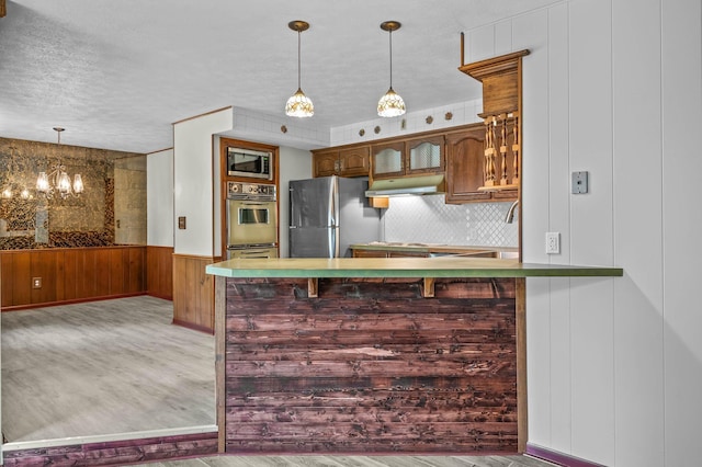 kitchen with appliances with stainless steel finishes, light hardwood / wood-style floors, a kitchen bar, and kitchen peninsula