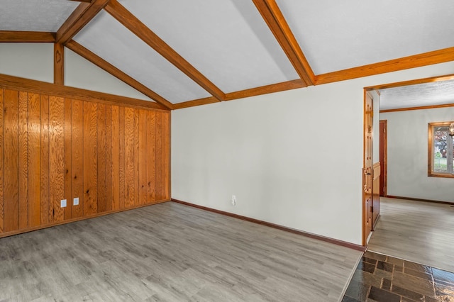 unfurnished living room featuring light wood-type flooring, wooden walls, and vaulted ceiling with beams