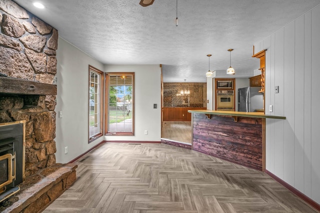 kitchen with stainless steel appliances, a textured ceiling, decorative light fixtures, a notable chandelier, and parquet floors