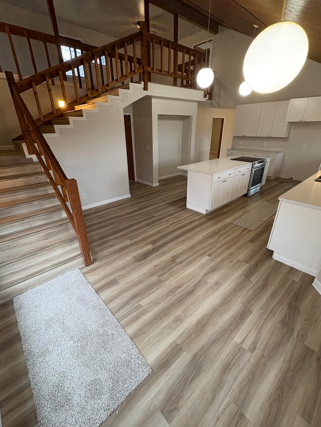 kitchen featuring white cabinets, a towering ceiling, light hardwood / wood-style flooring, and hanging light fixtures