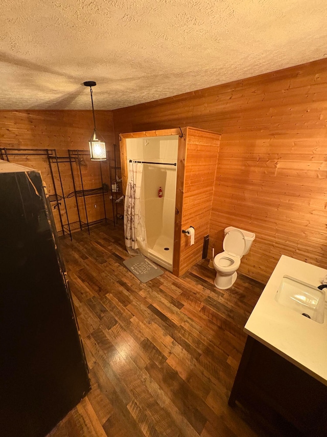 bathroom with wood-type flooring, a textured ceiling, walk in shower, and wood walls