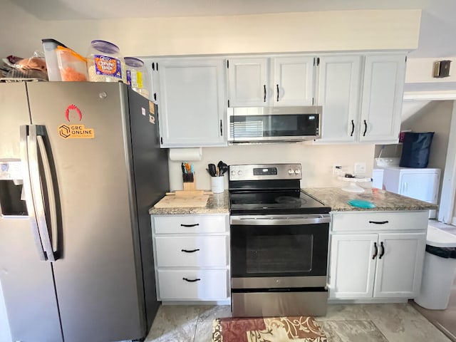 kitchen with washing machine and dryer, appliances with stainless steel finishes, light stone counters, and white cabinets