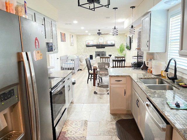 kitchen with white cabinetry, sink, appliances with stainless steel finishes, light stone countertops, and hanging light fixtures