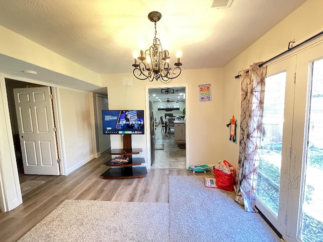 recreation room with hardwood / wood-style flooring, a chandelier, and a textured ceiling