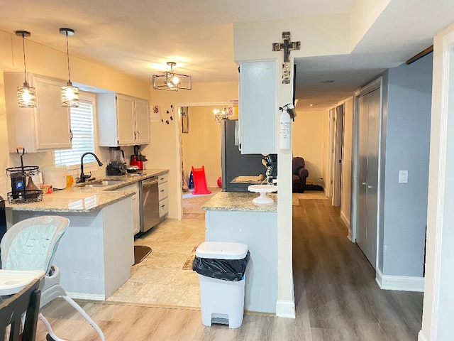 kitchen featuring stainless steel appliances, white cabinetry, sink, decorative light fixtures, and light hardwood / wood-style flooring