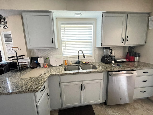 kitchen with tasteful backsplash, light stone countertops, sink, white cabinets, and stainless steel dishwasher