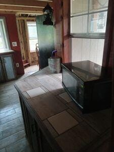 kitchen featuring tile counters, beam ceiling, and radiator