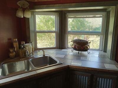 kitchen with a wealth of natural light, tile counters, and sink