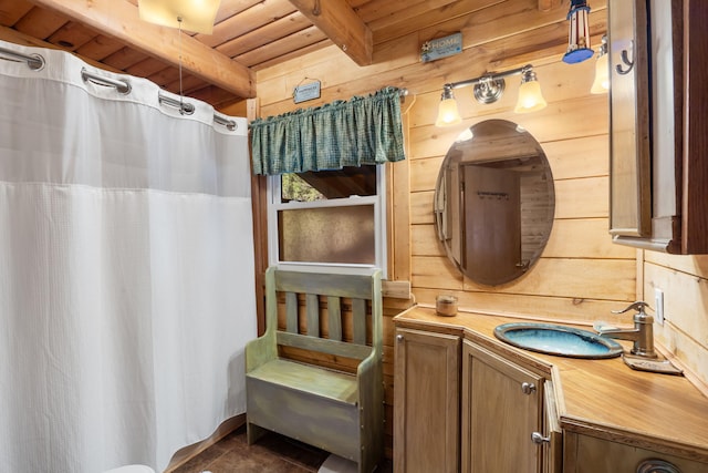 bathroom featuring beamed ceiling, wooden ceiling, vanity, and wood walls