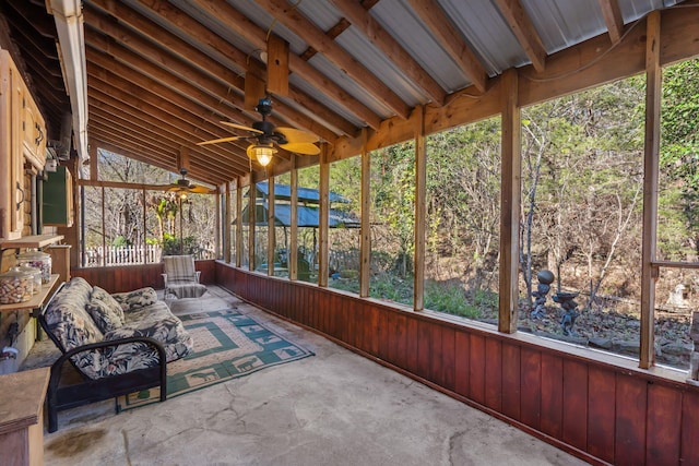 unfurnished sunroom with ceiling fan, plenty of natural light, and lofted ceiling with beams