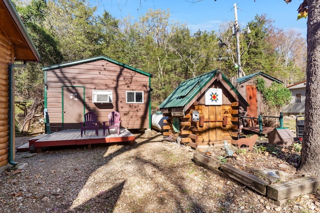 rear view of property featuring a wooden deck and a shed