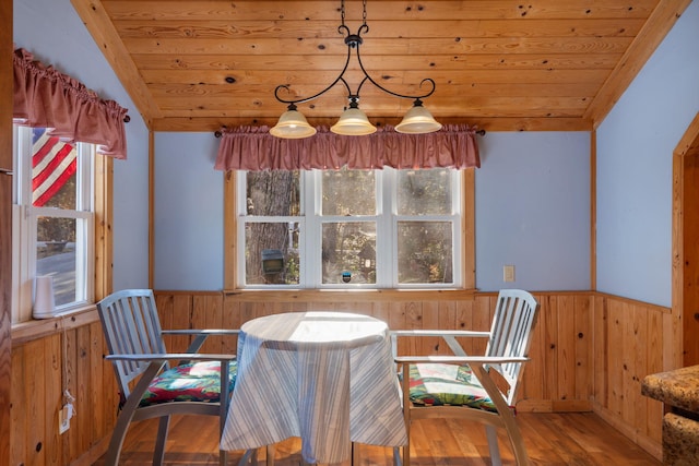 unfurnished dining area featuring hardwood / wood-style floors, wooden ceiling, and wood walls