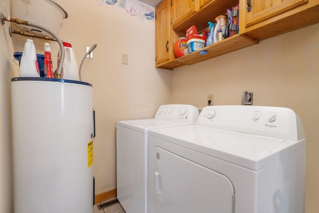 washroom featuring water heater, washer and clothes dryer, and cabinets