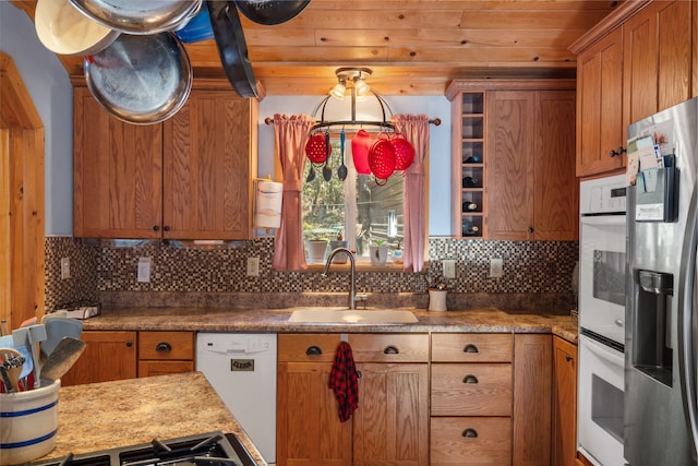 kitchen featuring white appliances, light stone countertops, sink, and backsplash