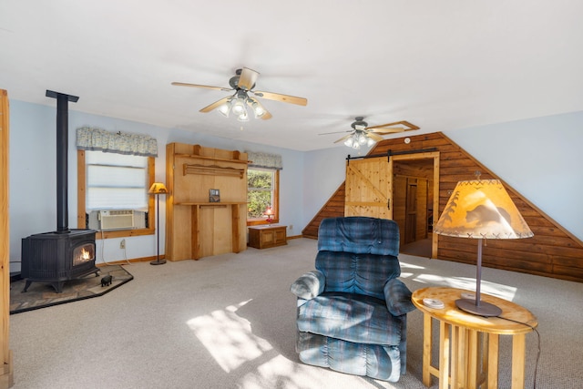 sitting room with a wood stove, carpet flooring, cooling unit, ceiling fan, and a barn door