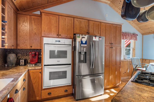 kitchen featuring lofted ceiling, wood ceiling, white double oven, and stainless steel refrigerator with ice dispenser